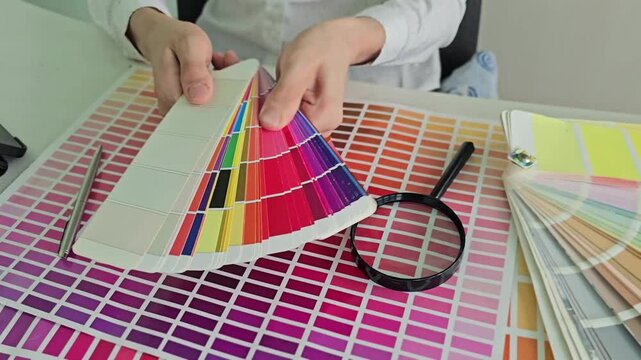 Choosing colors in a design studio while holding color swatches and examining options with a magnifying glass