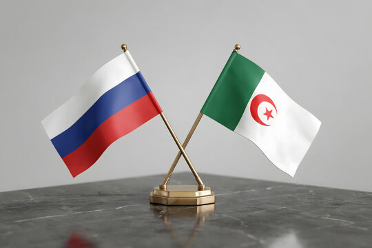 Miniature flags of russia and algeria on a dark marble table against a plain grey background, representing diplomatic and state relations