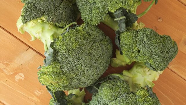 Fresh green broccoli florets rotating on a wooden table