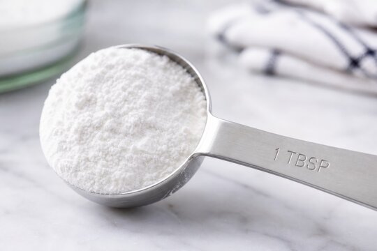 Measuring spoon with white powder on kitchen counter
