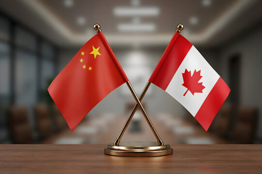 Small desk flags of china and canada standing on a wooden surface in a blurred office boardroom with soft lighting and dark furniture visible