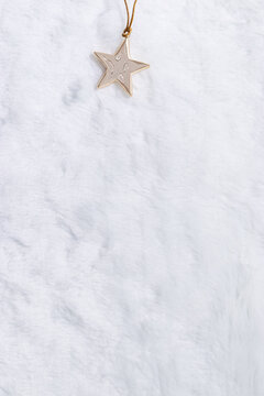 Christmas decoration glossy golden star on white fluffy fur, minimal new year top view. Gold Metallic star bauble shiny, glitter. Stylish holiday background with copy space, winter seasonal design