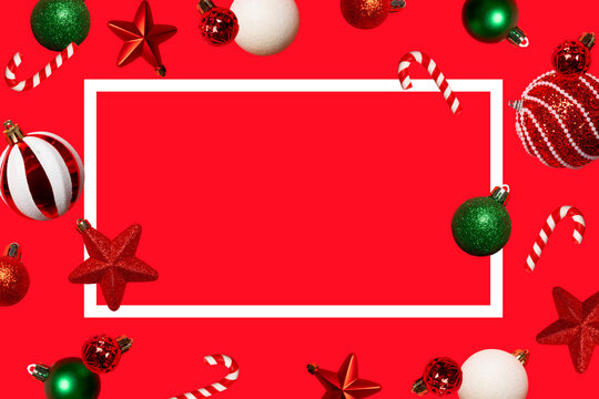 Festive Christmas background with a white rectangular frame, colorful ornaments, stars and candy canes on red. Ideal for greeting cards, banners, social media and holiday advertising.