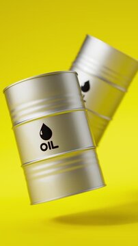 Two silver metal oil barrels floating on a yellow background for petroleum industry concept. Vertical video.