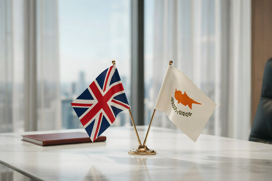 Small flags of the united kingdom and cyprus on a desk stand in a bright office with a notebook on a white marble surface for business meetings