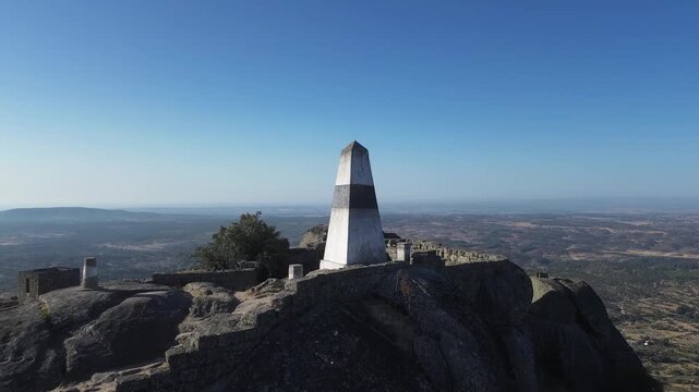 Triangulation pillar overlooking Monsanto, Portugal, with panoramic views across mountains and valleys. Historic high point surrounded by granite rocks and dramatic landscapes.
