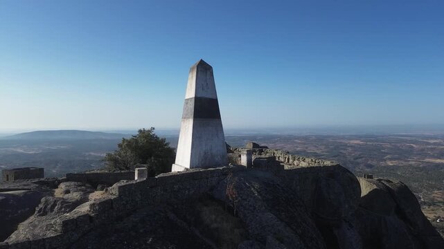 Triangulation pillar overlooking Monsanto, Portugal, with panoramic views across mountains and valleys. Historic high point surrounded by granite rocks and dramatic landscapes.