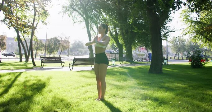 Yoga practice. Outdoor workout. Active sportive woman training body in natural sunlit green park performing healthy lifestyle.