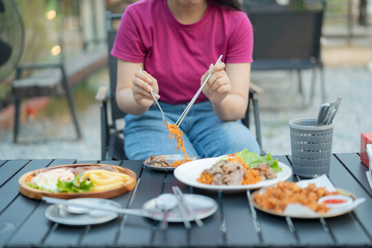 Woman eating a delicious meal at an outdoor restaurant with rice and meat dishes