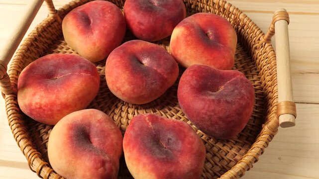 Ripe flat peaches in a wicker basket