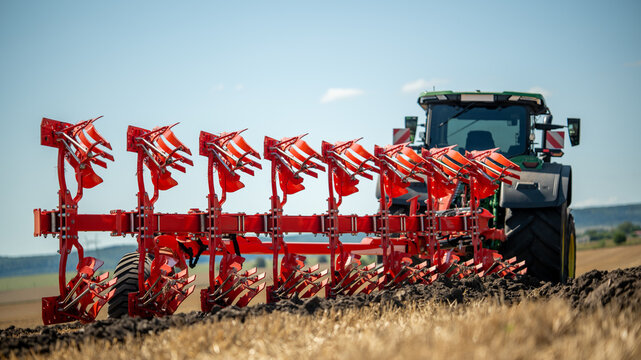 Farm tractor with a large plow working on a field during daylight hours in an open rural area