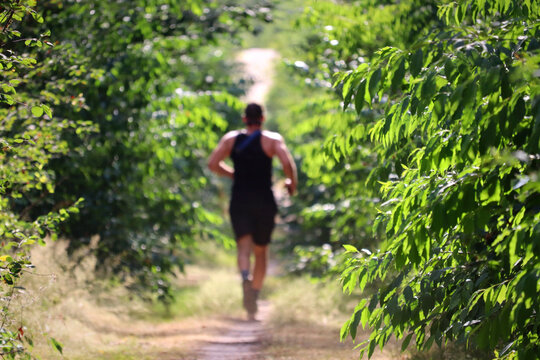 Man running through forest trail during workout