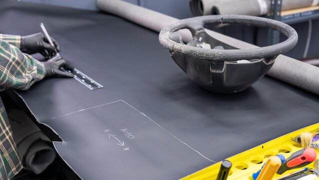 A seamstress in a workshop makes a new leather cover for a car steering wheel.