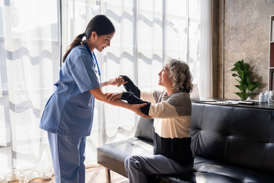Home Healthcare with Asian Nurse Assisting Older Patient Rehab E