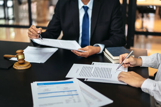 Two people are sitting at a table with papers and pens
