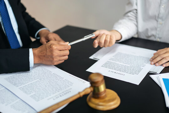 Two people are sitting at a table with papers and a gavel