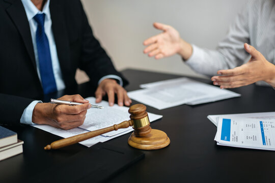 A man and a woman are sitting at a table with a judge and a gavel