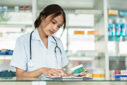 A woman in a white lab coat is looking at a tablet with a green sticker on it