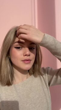 Young girl Posing for Camera with black Winged Eyeliner Makeup. Woman doing everyday casual makeup, drawing black eyeliner, eyeshadow, applies winged eyeliner to eyes. Vertical mobile ugc video