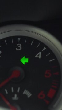 A driver presses the left turn-signal lever on a car dashboard, the illuminated arrow appears on the instrument panel with the ignition on, depicting a routine vehicle control check