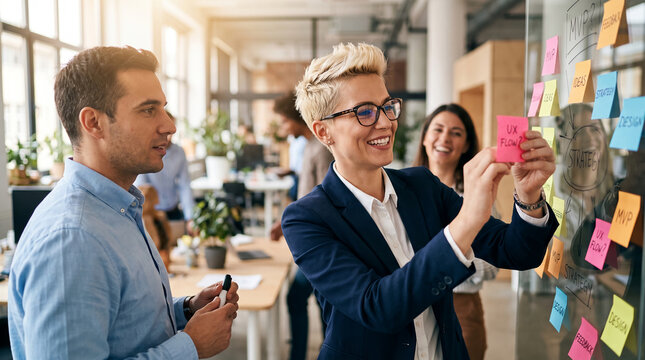 Team brainstorming with colorful sticky notes on a glass wall, visualizing strategy and ideas, representing collaboration and innovation in a modern office.