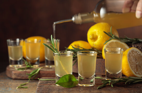 Italian liqueur Limoncello with fresh lemons and rosemary branches.