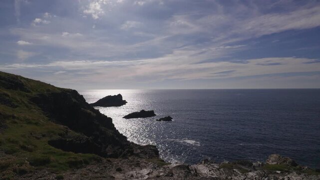 Views over the coastline from Pentre, Newquay, Cornwall, England during late afternoon, sun shimmering on the sea, Goose rock in the distance.
