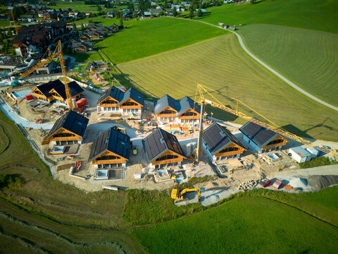 Tourist resort construction site with cranes, solar panels on a roof and swimming pools.
