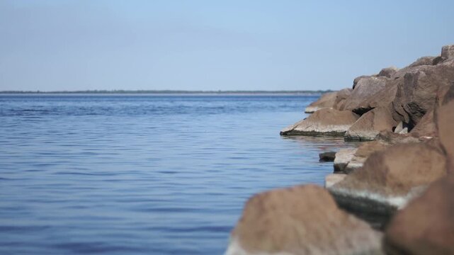Rocky breakwater beside calm water with selective focus