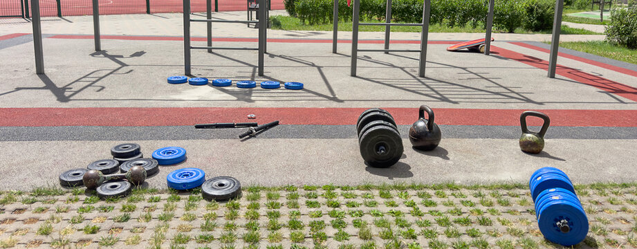 Outdoor gym equipment with dumbbells kettlebells weight plates and calisthenics workout area for strength training athletes