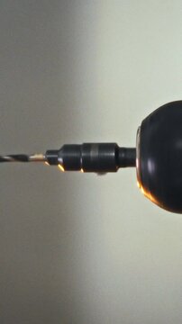 An electric drill spins a precision drill bit on its spindle in a workshop, illustrating technology for accurate drilling of various materials, supporting the fabrication of complex machines