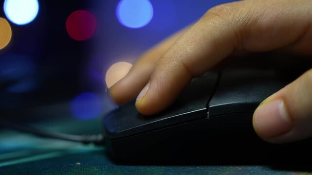 Close up of a hand using a computer mouse with blurred colorful lights in the background