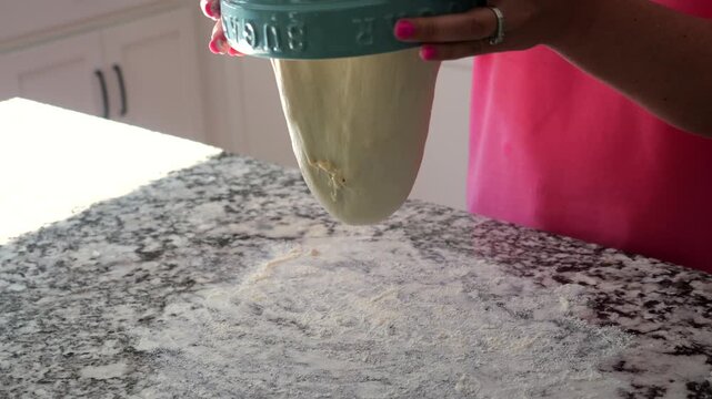 Baker stretch-and-folding sourdough dough, incorporating cheese, resting on granite countertop before baking into a golden, artisanal loaf of bread