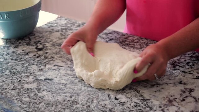 Baker stretch-and-folding sourdough dough, incorporating cheese, resting on granite countertop before baking into a golden, artisanal loaf of bread