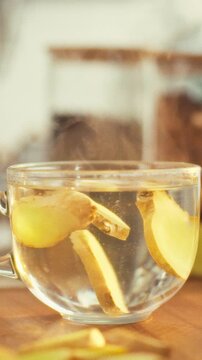 Freshly sliced ginger root spirals in clear cup, rhizome releasing minerals and anti-inflammatory compounds into the liquid, creating vivid infusion of pungent extract for health-focused preparation