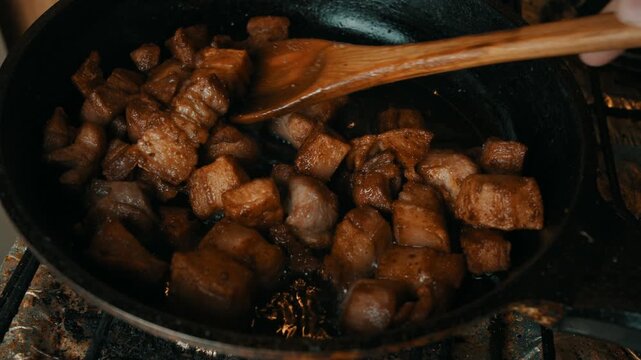 High Angle Close Up Shot of Crispy Pork Belly Piece Held on Wooden Spoon