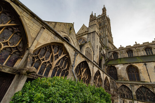 Intricate Gothic tracery windows and stonework of Gloucester Cathedral courtyard