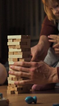 Mom, dad and their young daughter sit on the living-room floor, each holding a piece of a board game, the family plays together in a quiet home setting, emphasizing shared activity and togetherness