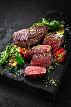 BBQ broiled gry aged roastbeef with roasted vegetable served as close-up on a rustic wooden board