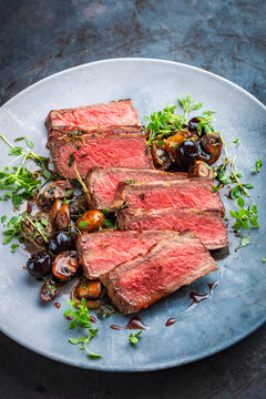 Traditional barbecue grass-fed dry aged roast beef steak tagliata with grilled mushrooms and fresh greens and herbs - meat food recipe
