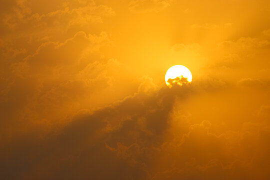 Serene Golden Sunrise Glowing Behind Soft Mist and Clouds. Golden Sun Shining Brightly Through Soft Amber Clouds