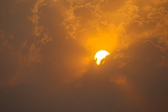 Serene Golden Sunrise Glowing Behind Soft Mist and Clouds. Golden Sun Shining Brightly Through Soft Amber Clouds