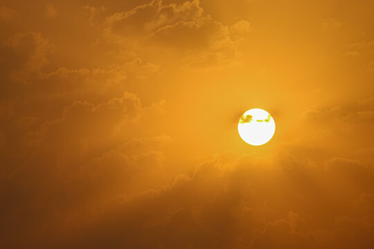 Serene Golden Sunrise Glowing Behind Soft Mist and Clouds. Golden Sun Shining Brightly Through Soft Amber Clouds