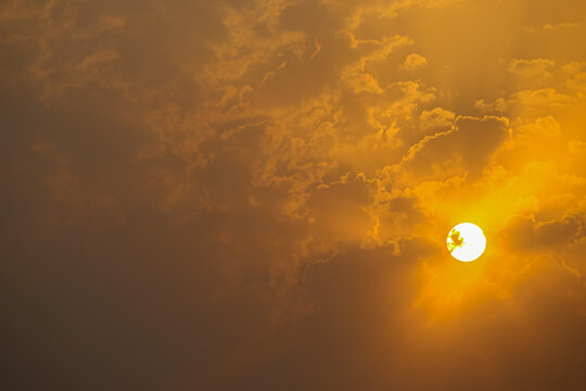 Serene Golden Sunrise Glowing Behind Soft Mist and Clouds. Golden Sun Shining Brightly Through Soft Amber Clouds