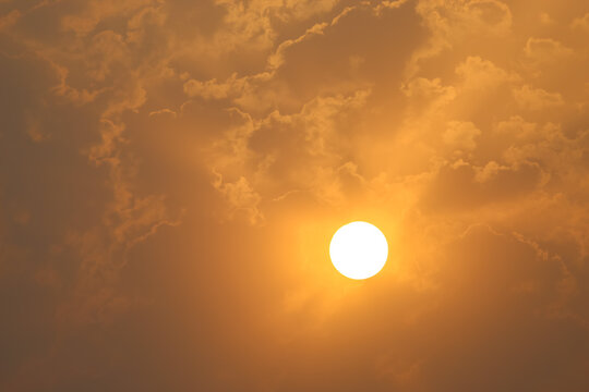 Serene Golden Sunrise Glowing Behind Soft Mist and Clouds. Golden Sun Shining Brightly Through Soft Amber Clouds
