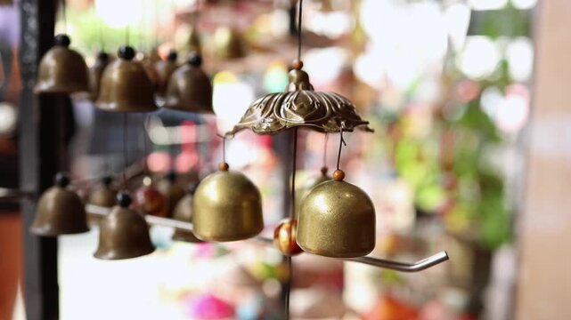 Traditional brass wind chime bells with wooden beads hanging on display in a souvenir shop in Nha Trang, Vietnam. Bronze feng shui bells in local Asian gift store, travel and tourism concept.