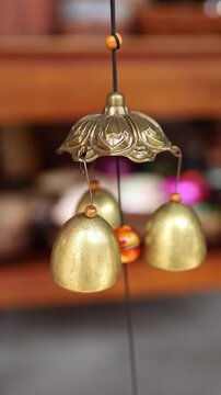 Traditional brass wind chime bells with wooden beads hanging on display in a souvenir shop in Nha Trang, Vietnam. Bronze feng shui bells in local Asian gift store, travel and tourism concept.