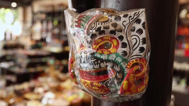 Traditional hand painted wooden theater mask wrapped in plastic displayed in a souvenir shop in Nha Trang, Vietnam. Traditional Asian folk craft souvenir hanging in local gift store, travel concept.