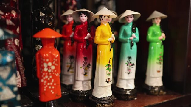 Traditional doll figurines of Vietnamese women in colorful Ao Dai dresses and conical hats displayed in a souvenir shop in Nha Trang, Vietnam. Local handcrafted ceramic statues, travel concept.