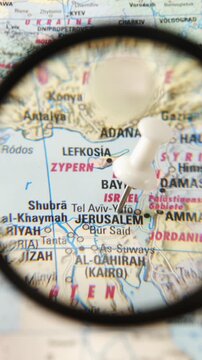 Magnifying glass highlights Jerusalem on a paper map of Europe